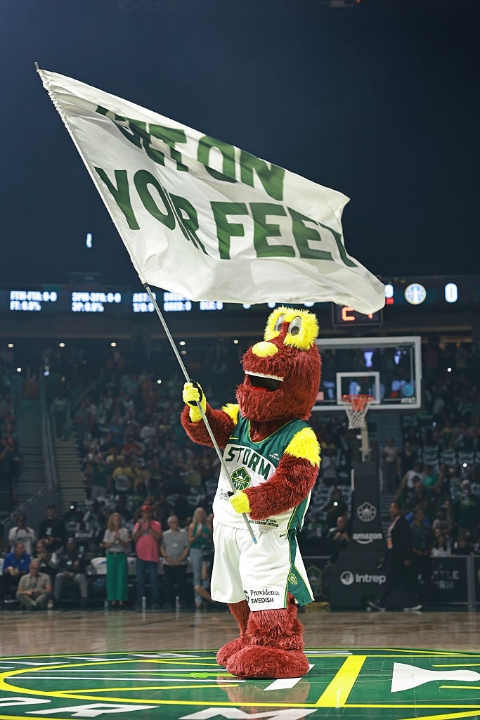 Basketballmaskot på banen vifter med et stort flagg der det står