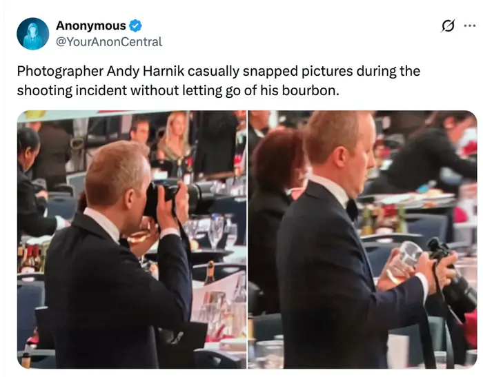En mann i dress holder et kamera i den ene hånden og en drink i den andre på et arrangement, avbildet i en tweet som fremhever denne scenen