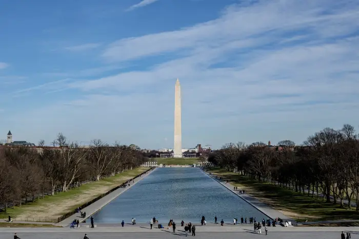 Washington Monument utsikt med Reflection Pool, folk som går i nærheten. Klar himmel, ikonisk amerikansk landemerke