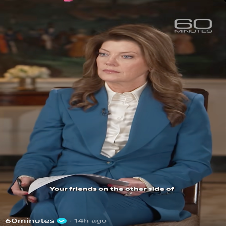 En person i en profesjonell blå dress sitter og holder notater under et "60 Minutes"-intervju. Undertekster er delvis synlige
