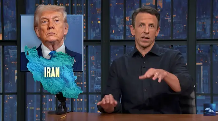 TV-vert Seth Meyers gester mens han sitter ved et bilde av Iran overtrukket med Donald Trump's ansikt