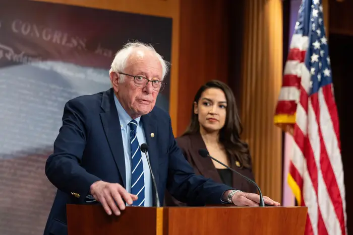 To personer står ved et podium under en pressekonferanse. Et amerikansk flagg er i bakgrunnen