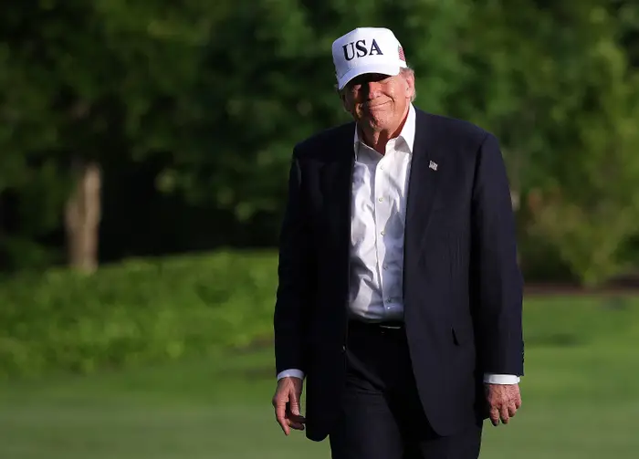 Mann i dress og "USA" cap gå utendørs på gress, smilende