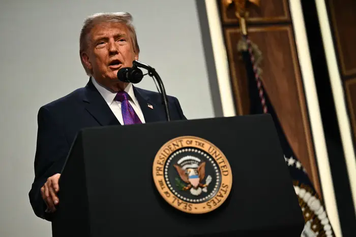 En mann i dress taler ved et podium med den amerikanske presidentens segl foran seg