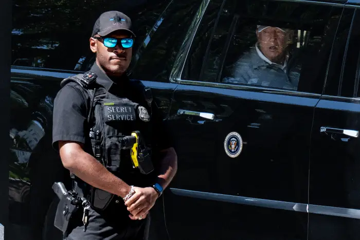 En Secret Service-agent står våken ved siden av et presidentkjøretøy med en passasjer synlig inni