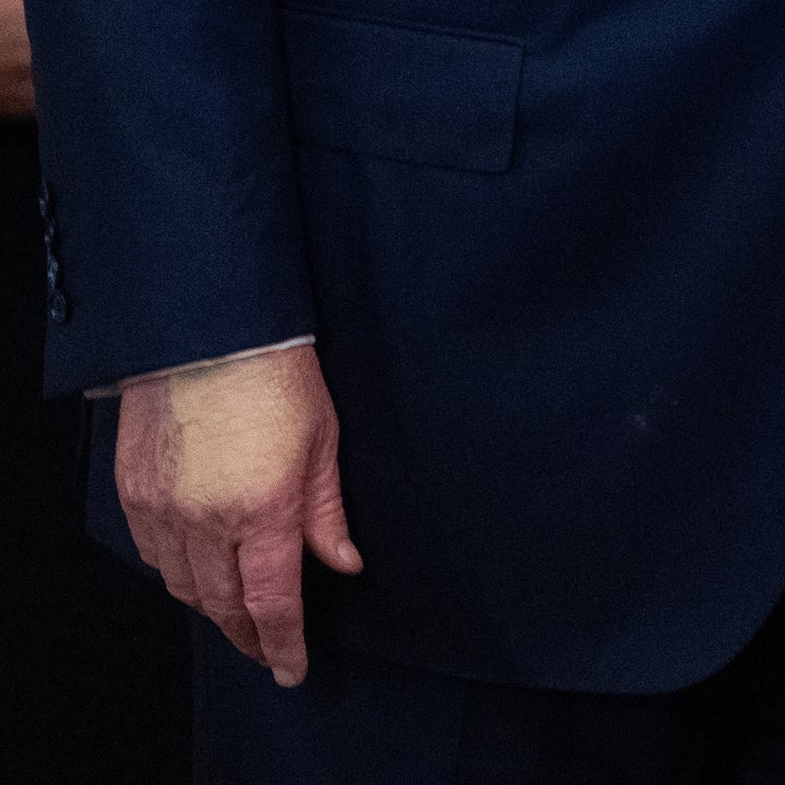 Nærbilde av en person i formell antrekk, iført en skreddersydd dress med hendene synlige på siden
