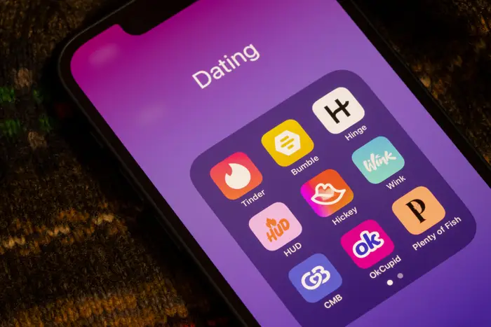 Smarttelefon som viser forskjellige datingapper, inkludert Tinder, Bumble, Hinge og OkCupid, på en lilla bakgrunn