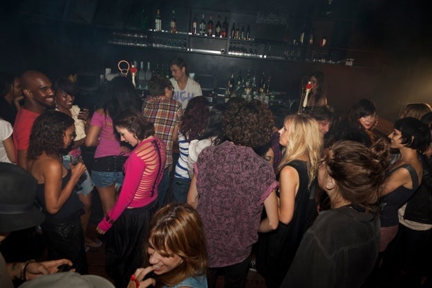 En livlig nattklubbscene med folk som danser og sosialiserer seg nær en bar, og fanger en pulserende nattelivsatmosfære