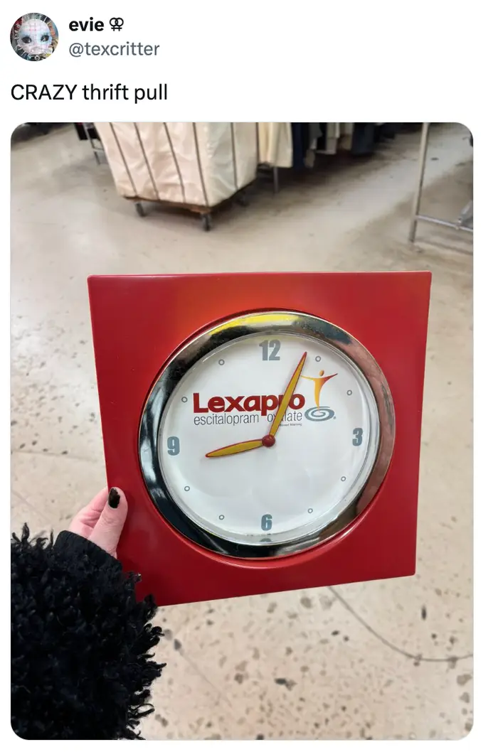 Person som holder en rød firkantet veggklokke med en Lexapro-logo på urskiven, funnet i en bruktbutikk