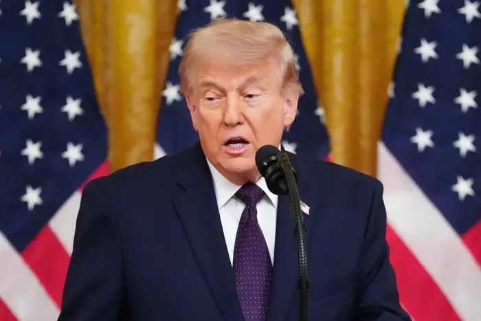 En person i dress snakker på et podium foran amerikanske flagg