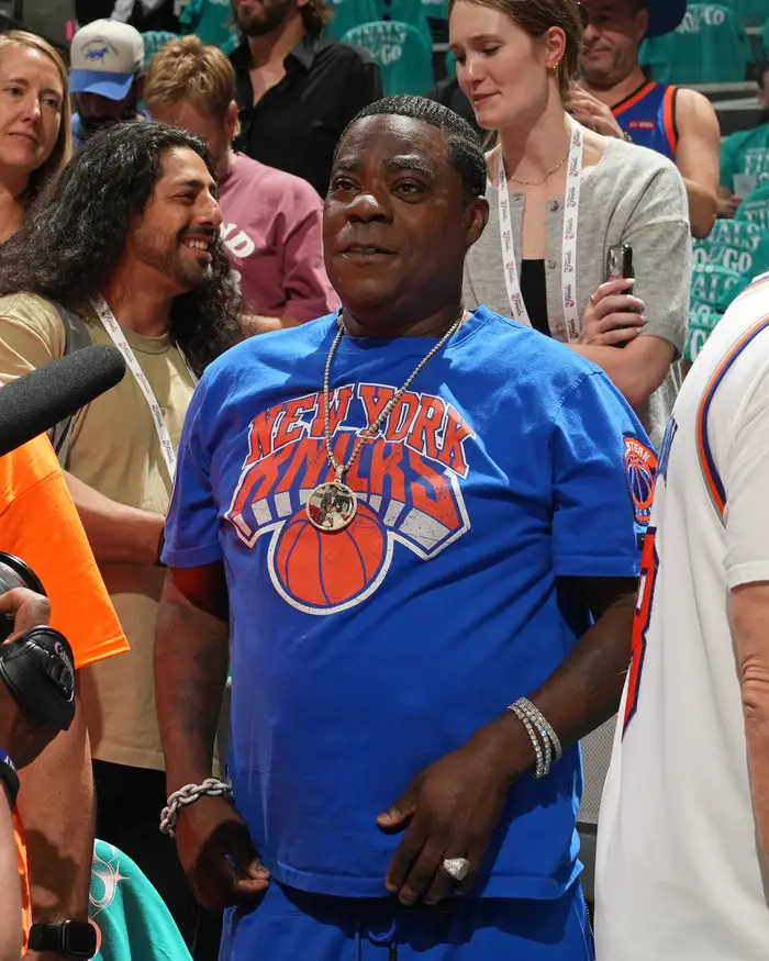 Person i en New York Knicks T-skjorte som deltar på et offentlig arrangement, omgitt av mennesker og presse