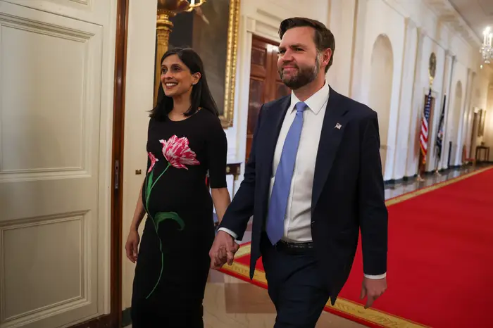 Et par går hånd i hånd i en formell setting; kvinnen har på seg en blomstermønstret kjole, og mannen er i dress