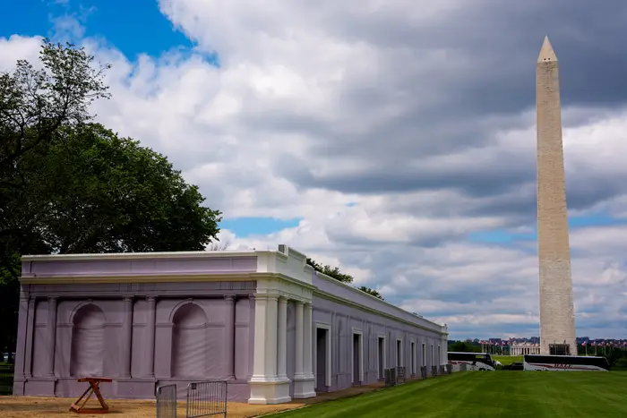 En lang struktur som ligner en klassisk fasade er plassert på National Mall, med Washington-monumentet synlig i bakgrunnen
