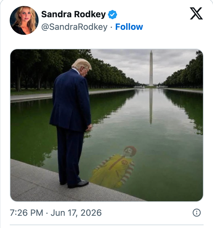 En mann i dress står ved et reflekterende basseng og ser et bilde av en klovn i vannet. Washington Monument er synlig i bakgrunnen