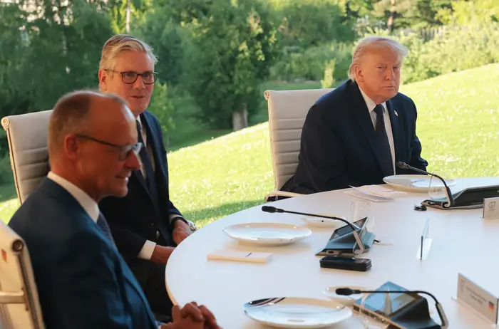 Donald Trump og Storbritannias statsminister Keir Starmer sitter ved et rundt bord utendørs, og ser ut til å være engasjert i samtale