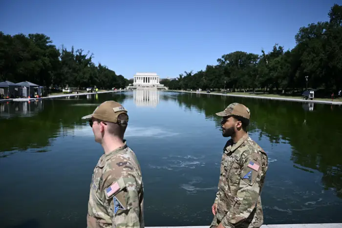 To militærpersonell i uniform står nær det reflekterende bassenget med Lincoln Memorial i bakgrunnen