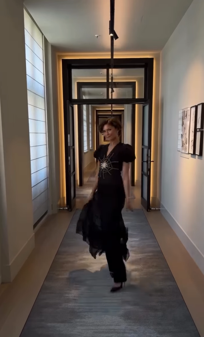 Zendaya går ned en gang i en stilig svart kjole med puffede ermer og et dekorativt design foran