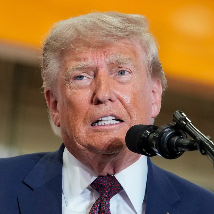 En person i dress taler ved et podium med en presidentsegl, inne i et stort lokale