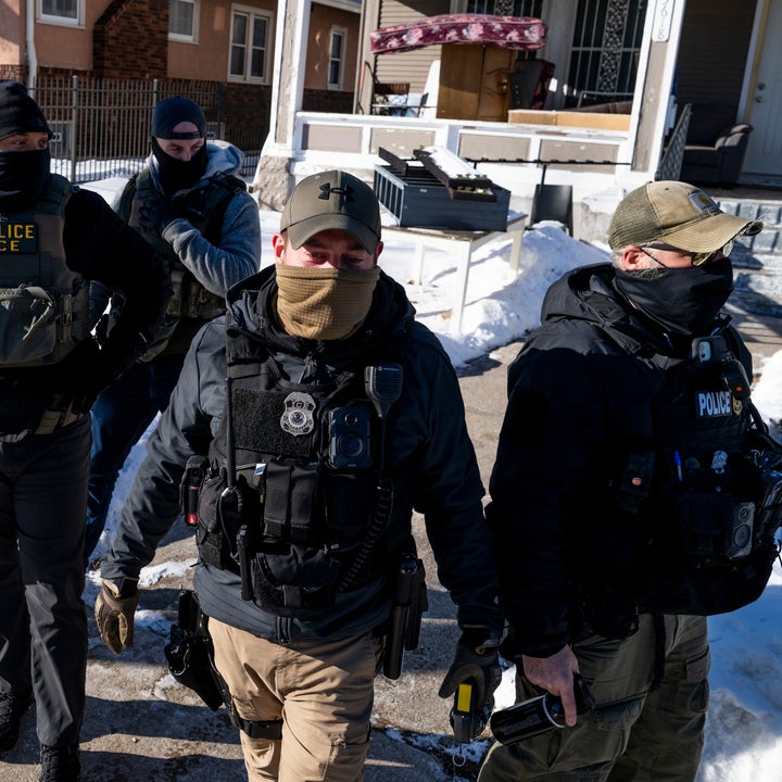 Gruppe lovhåndhevere i taktisk utstyr og masker som går på en snødekt gate