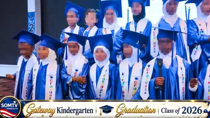 Barn i blå konfirmasjonscapser og -kjoler står på en barnehageavslutningsseremoni for klassen 2026, iført bånd som sier «graduate».