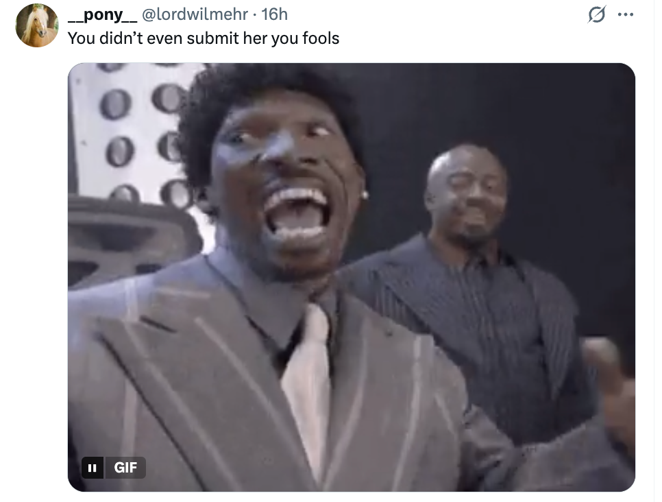 En mann i dress utbryter animert med vidåpen munn i et humoristisk eller overrasket uttrykk. En annen mann i dress står bak ham