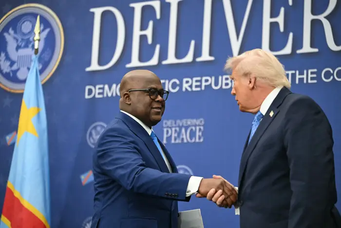 To ledere i dress håndhilser på et internasjonalt arrangement med fokus på fred i Den demokratiske republikken Kongo
