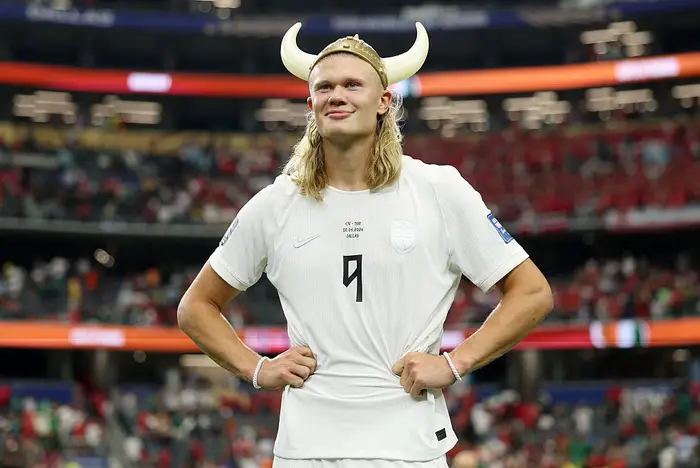 Person i en fotballuniform med en vikinghjelm med horn, står selvsikkert på et stadion