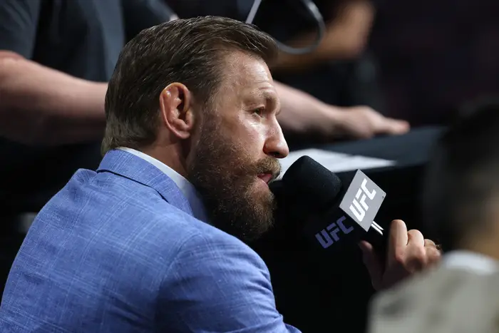 Conor McGregor i dress snakker inn i en UFC-mikrofon på et arrangement