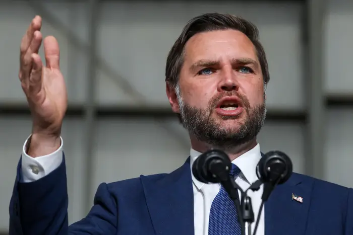 En person i dress snakker lidenskapelig ved et podium og gestikulerer med en hånd hevet