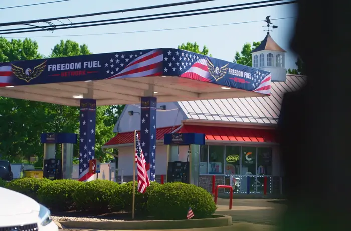 En Freedom Fuel bensinstasjon med patriotisk dekor, med amerikanske flaggelementer på kalesjen og et lite flagg ved inngangen