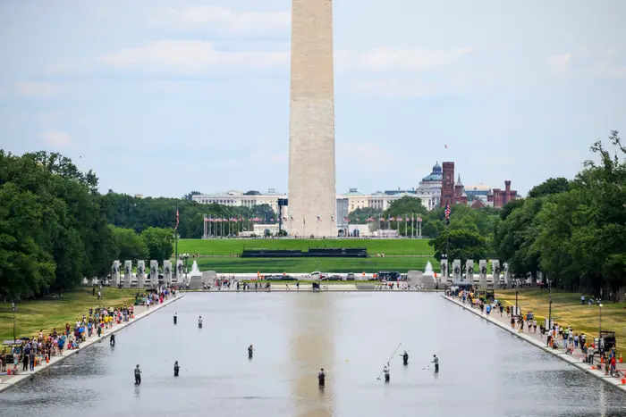 Vid utsikt over Washington-monumentet med folk som går rundt det reflekterende bassenget på en klar dag
