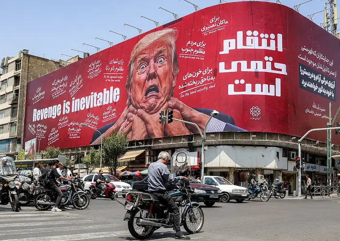 Stor reklametavle i en by viser en karikatur av Donald Trump som blir kvalt, omgitt av persisk tekst og uttrykket 