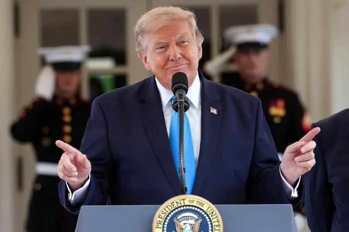 En person i dress taler ved et podium med en presidentsegl, flankert av militært personell i uniform
