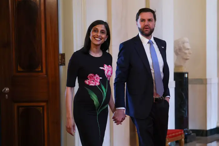 Et par går hånd i hånd. Kvinnen har på seg en blomsterkjole, og mannen er i dress og slips. De ser ut til å være på et formelt arrangement