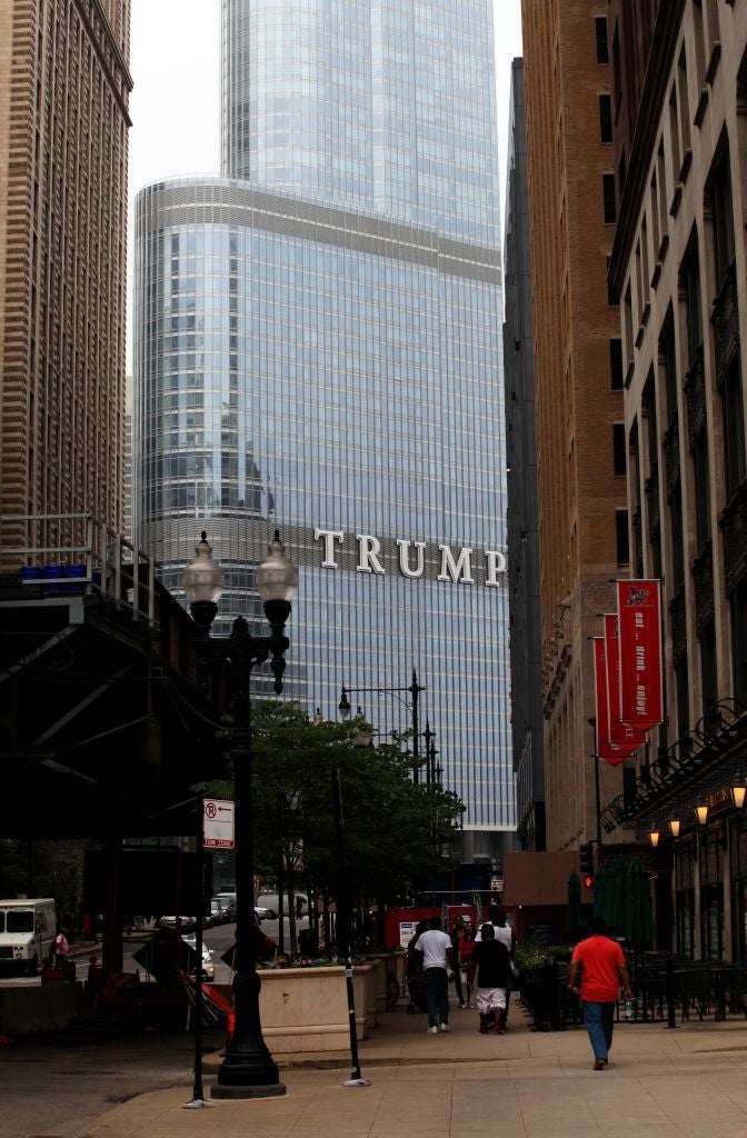En utsikt over Trump Tower fra en bygate, omgitt av høye bygninger, med folk som går på fortauet nedenfor