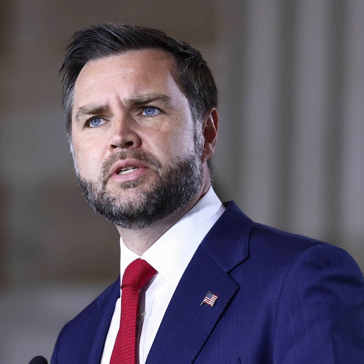 Jeg vet ikke hvem denne personen er, men de snakker på et podium, iført dress og slips, og virker engasjert i talen sin
