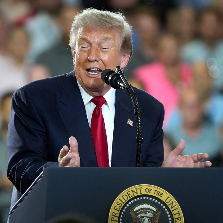 En person som taler ved et podium med en presidentsegl og henvender seg til et publikum