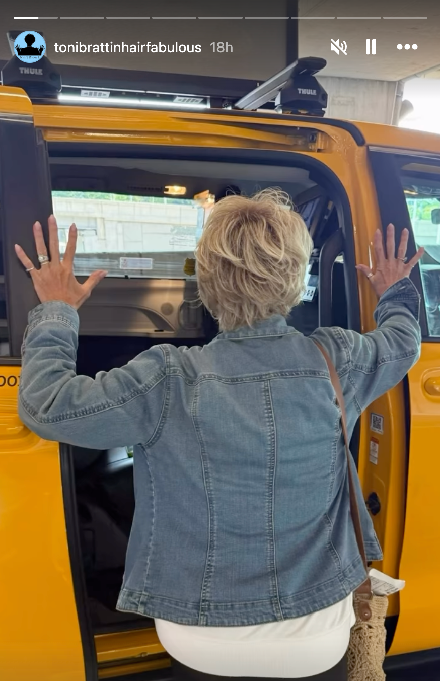 Person som står overfor en gul taxi med hendene hevet på døren, iført dongerijakke og hvite bukser