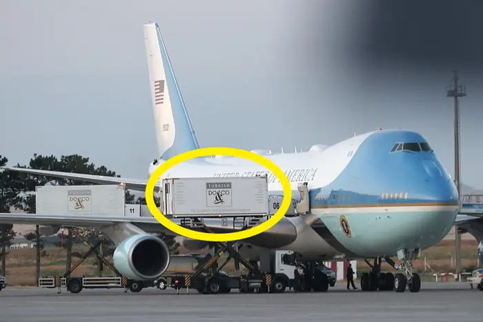 Fly på asfalt med last som lastes. Flyet bærer markeringer og segl til USAs president