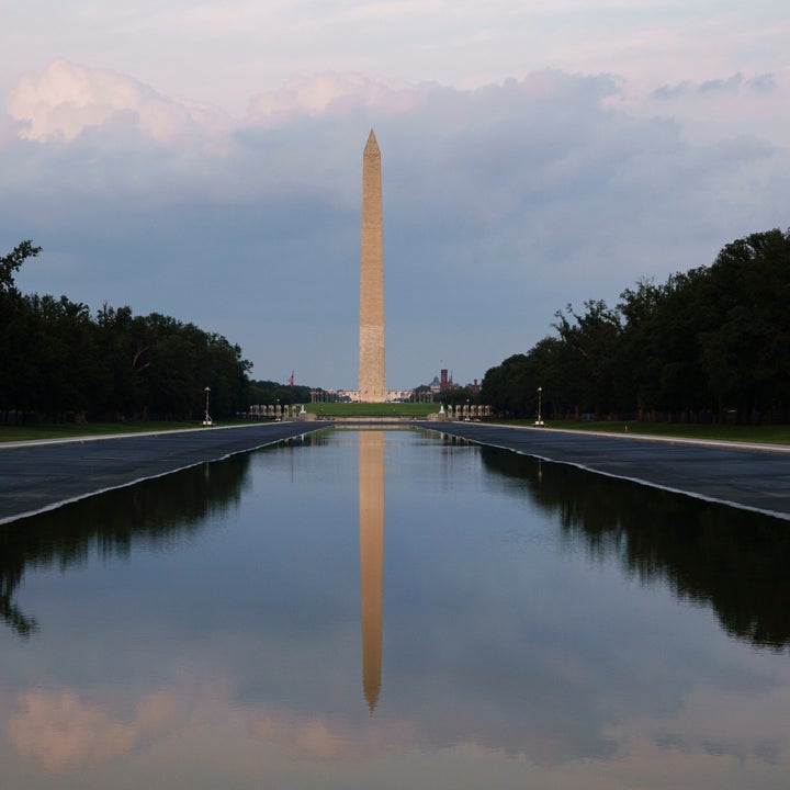 Washington-monumentet speiler seg i et rolig basseng, omgitt av trær og åpen himmel
