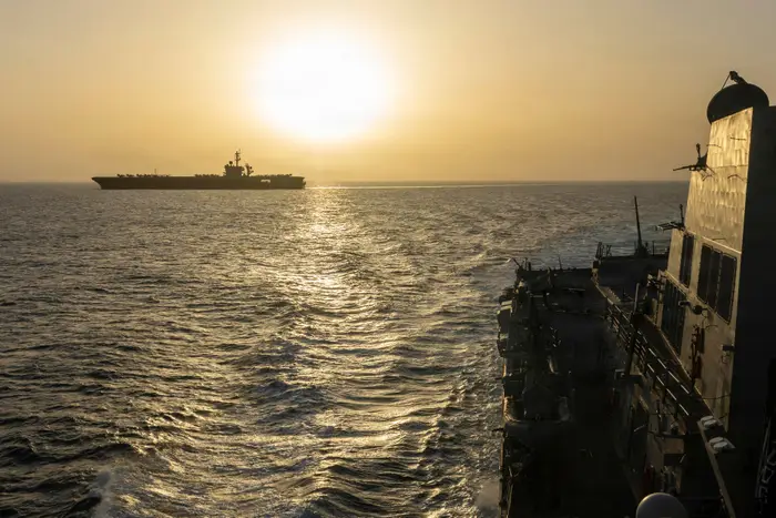 To marineskip på havet under solnedgang, seiler parallelt med hverandre med horisonten synlig