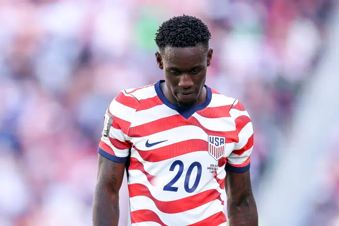 Fotballspiller i USA-drakt med nummer 20, hodet lett ned, på banen under en kamp