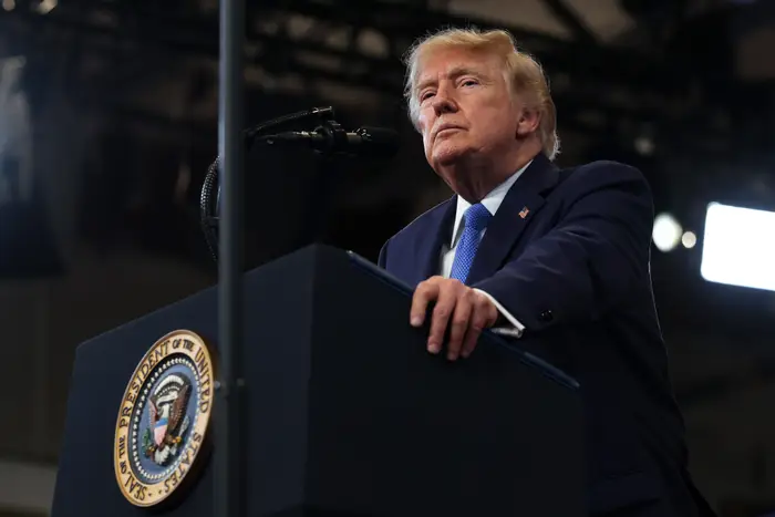 En mann på et podium med en presidentsegl, snakker i en mikrofon på et arrangement