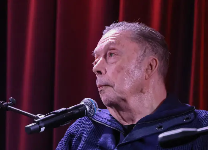 Tim Curry ser til siden med en mikrofon plassert foran seg