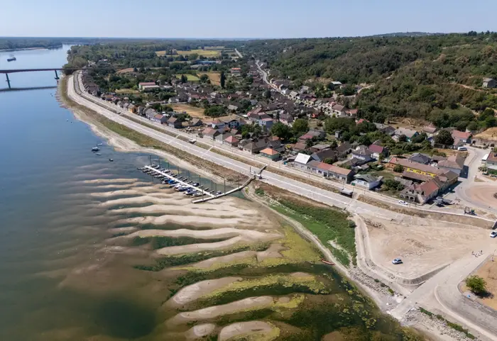 Luftfoto av en by ved elvebredden med hus, en bro og en liten marina langs vannkanten