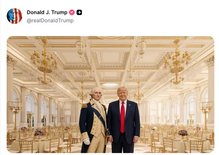 En figur kledd som George Washington står ved siden av en mann i dress og rødt slips i en elegant ballsal med lysekroner