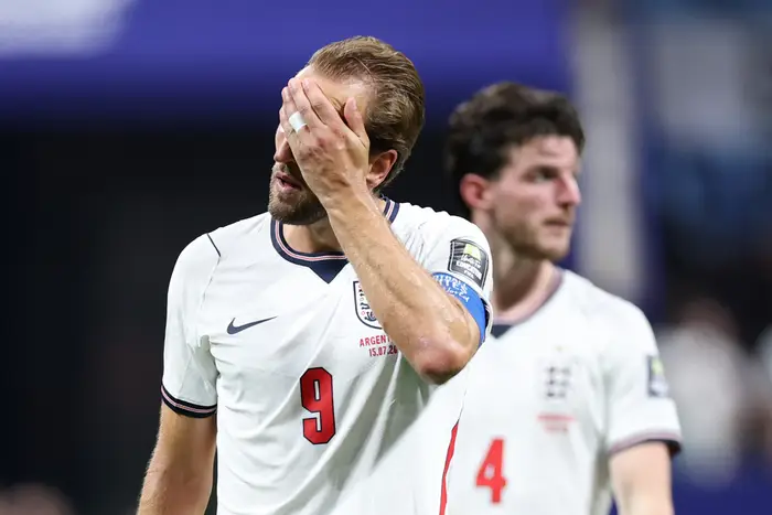 Fotballspiller i hvit trøye med nummer 9 dekker ansiktet med hånden; en annen spiller står bak ham