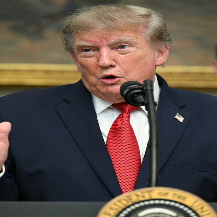 En person i dress snakker ved et podium med presidentseglet, med en person som står i bakgrunnen
