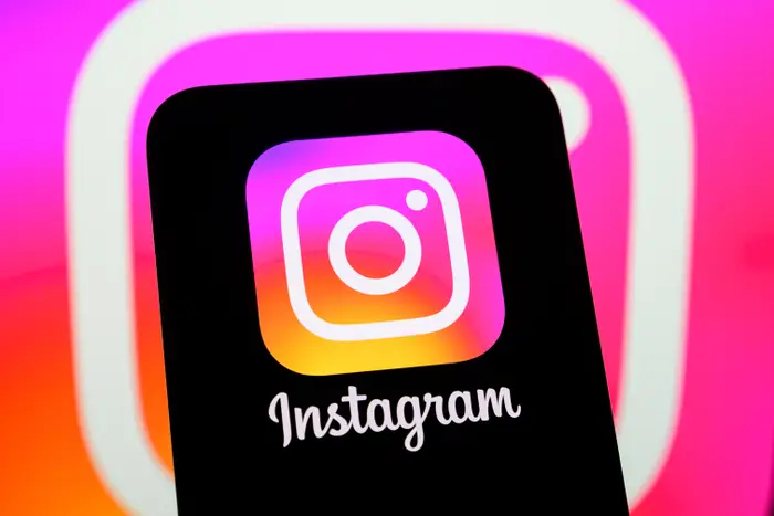 Instagram-logo på en smarttelefonskjerm foran en uskarp Instagram-bakgrunn