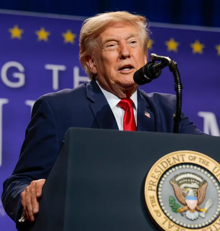 En mann taler ved et podium med et presidentstempel, og holder en tale ved et arrangement